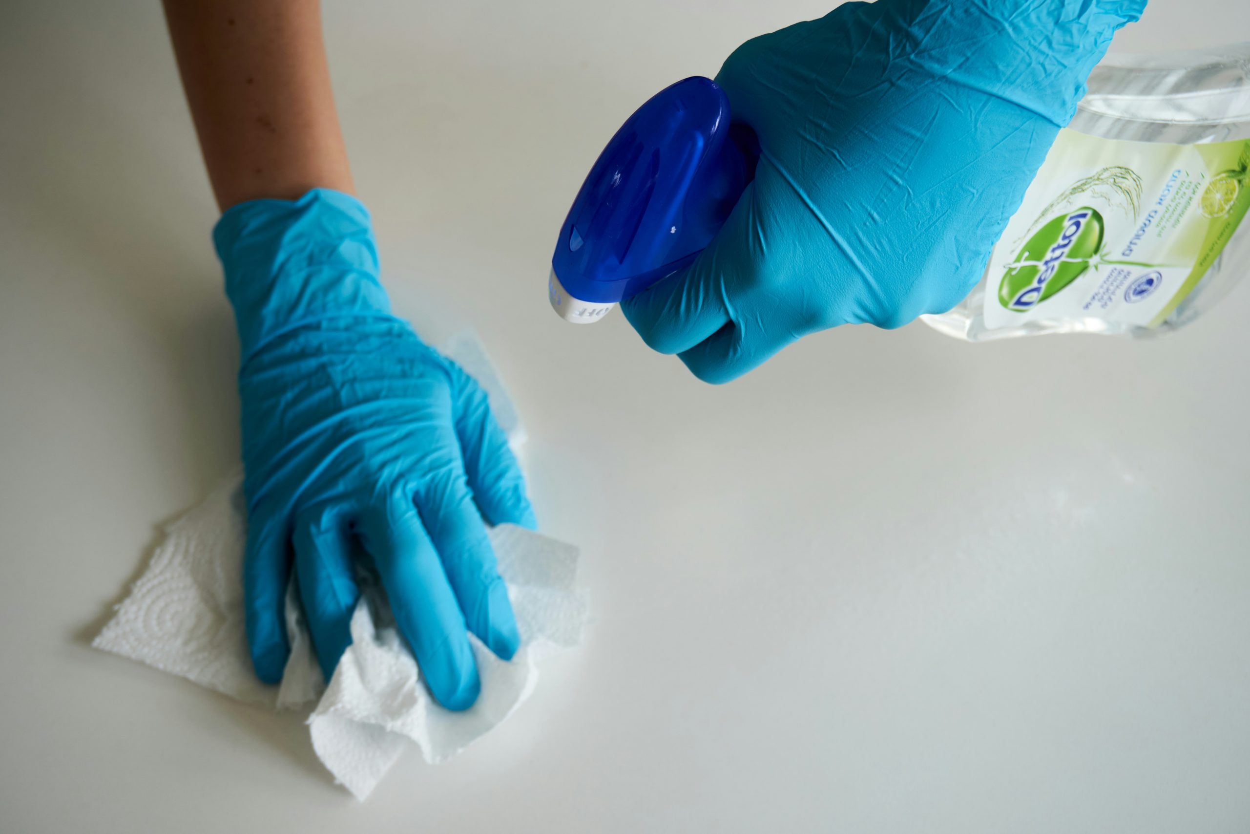 Désinfection d'une surface avec spray et gants bleus